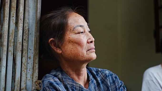 Bà Nguyễn Thị Thao lặng im, buồn bã khi chứng kiến những ngôi nhà tan hoang bởi dòng nước dữ. Ảnh: Hùng Khang.