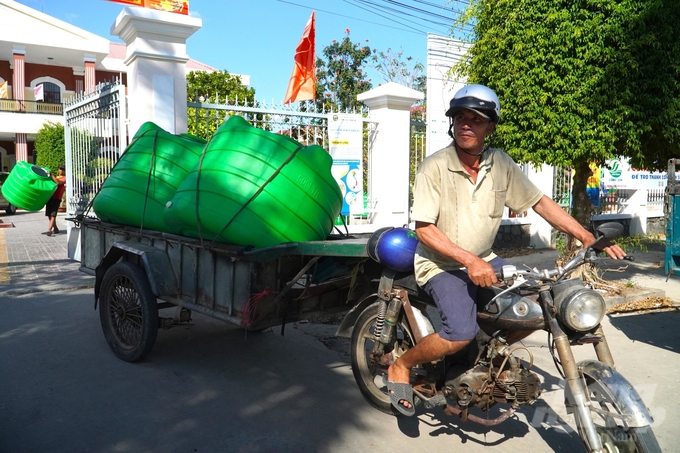Một số người dân địa phương hỗ trợ chở bồn nước về tận nhà cho những người già. Ảnh: Kim Anh.