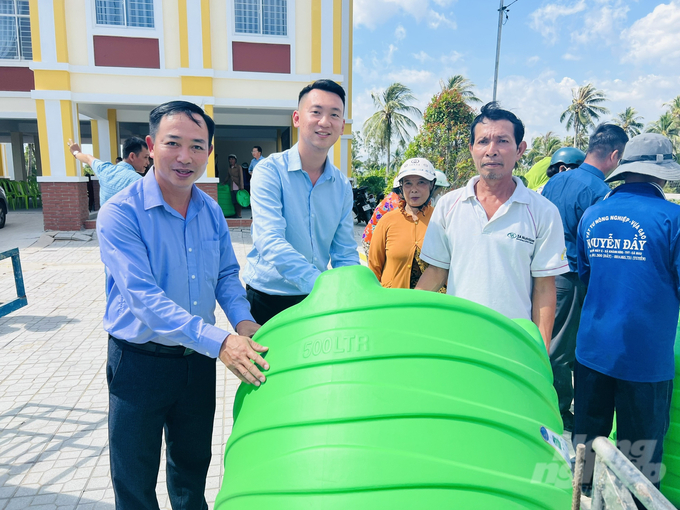 Ông Lư Phạm Minh Tuấn (giữa), Phó Giám đốc Kinh doanh và Maketing, trợ lý Tổng Giám đốc và ông Nguyễn Ngọc Thắng (ngoài cùng bên trái), Trưởng VPĐD Báo Nông nghiệp Việt Nam tại ĐBSCL tặng bồn nước cho các hộ dân xã Khánh Bình Tây. Ảnh: Trọng Linh. 