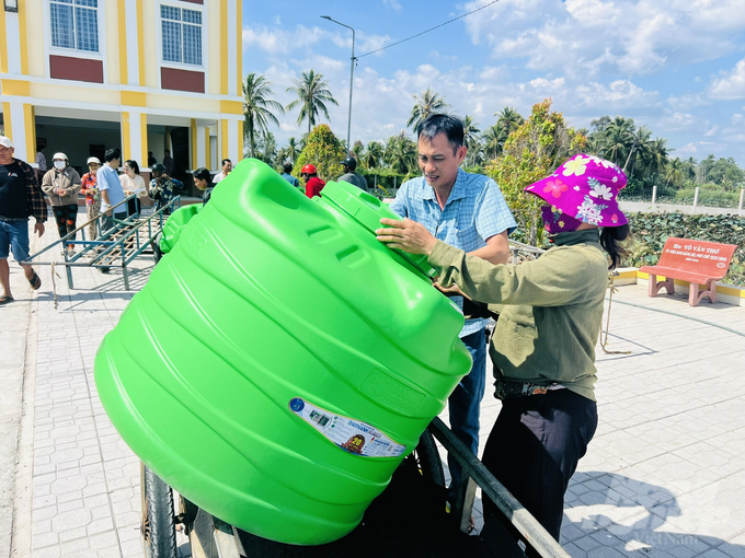 Cán bộ xã Khánh Bình Tây giúp người dân chở bồn nước về nhà. Ảnh: Trọng Linh.