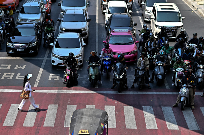 Những người đi xe máy chờ đèn đỏ dưới bóng râm tại thủ đô Bangkok, Thái Lan, ngày 25/4. Ảnh: AFP.