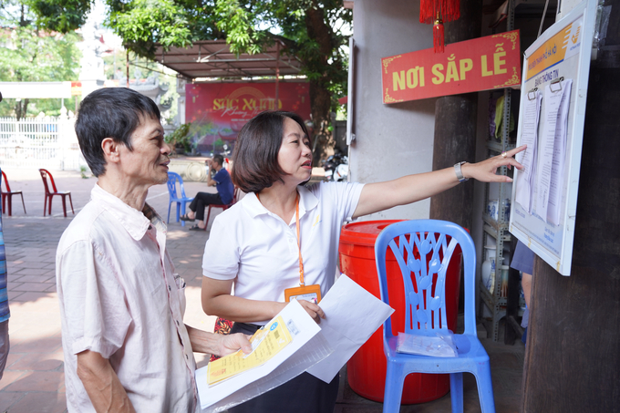 Nhân viên Bưu điện Việt Nam hỗ trợ người nhận tiền trợ cấp. Ảnh: VNP.