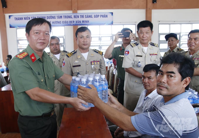 Trung tá Nguyễn Đức Hậu, Trưởng phòng Hậu cần, Công an tỉnh An Giang trao nước suối cho người dân. Ảnh: TT.