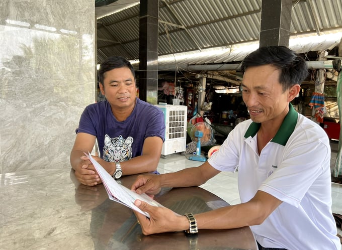 Mr. Binh (left) recounting his experience of being bitten by a rabid dog. with a veterinary officer in My Quy Tay Commune. Photo: Thanh Son.