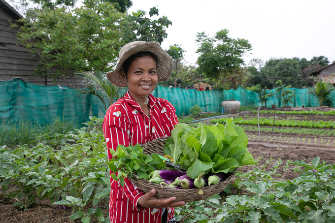 A woman farmer with a basket of harvested vegetables.