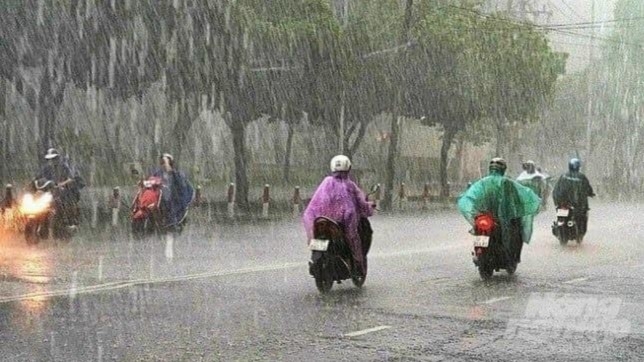 Người dân mặc áo mưa lưu thông trên đường sau cơn mưa bất chợt. Ảnh: Trần Phi.