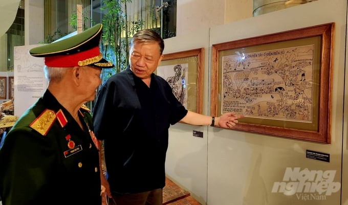 Đại tướng Tô Lâm, con rể họa sỹ Ngô Mạnh Lân, giới thiệu các tác phẩm của cha vợ mình sáng tác tại chiến trường Điện Biên Phủ. Ảnh: Vân Anh.
