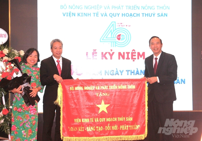 Thứ trưởng Phùng Đức Tiến trao cờ in dòng chữ 'Đoàn kết, sáng tạo, đổi mới, phát triển' của Bộ NN-PTNT cho Viện Kinh tế và Quy hoạch thủy sản. Ảnh: Trung Quân.