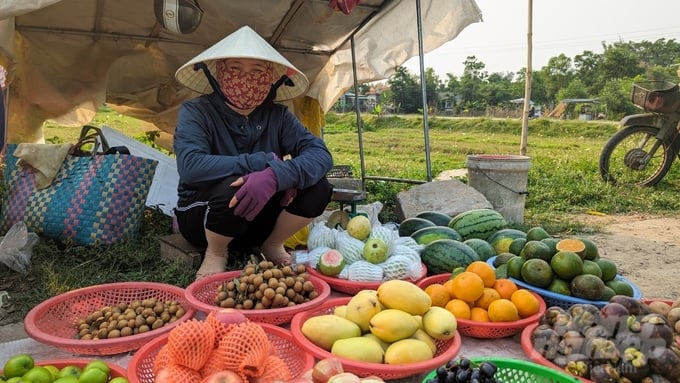 Vợ một ngư dân ở phá Tam Giang tranh thủ thời gian chồng đi bủa lưới bày bán các loại trái cây để cải thiện thu nhập. Ảnh: Công Điền.