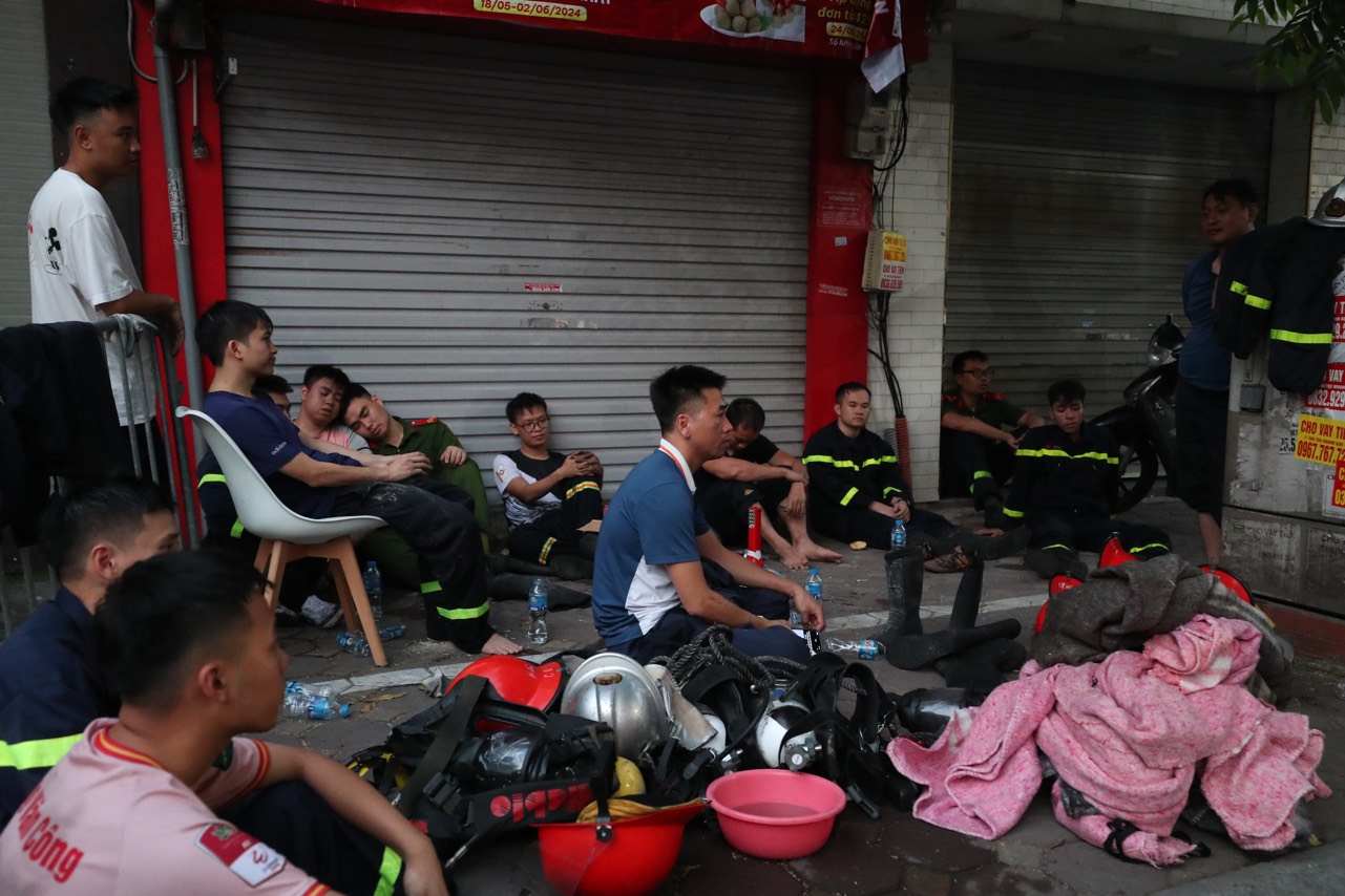 Lực lượng chữa cháy nghỉ ngơi ngay trên hè phố Trung Kính sau một đêm làm việc cật lực.
