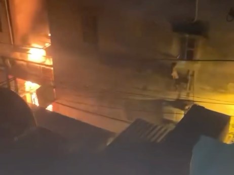 Hình ảnh chụp từ clip đăng tải trên mạng xã hội hình ảnh một thanh niên bắc thang đập tường cứu người trong vụ hỏa hoạn tại phố Trung Hòa. Ảnh: MXH.
