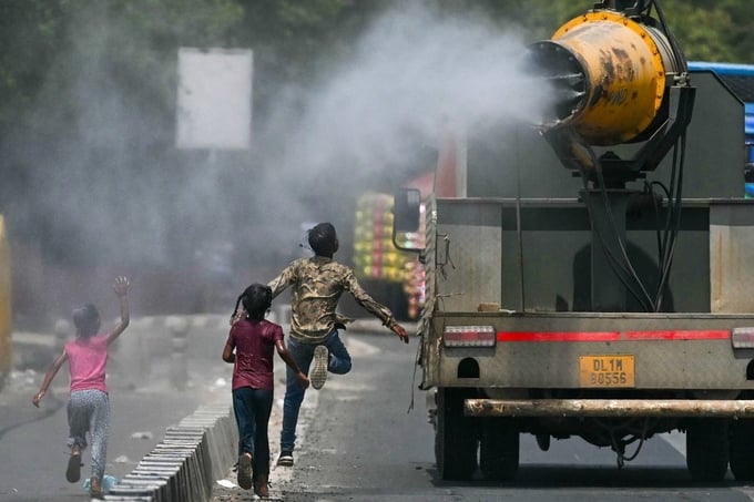 Trẻ em chạy theo xe phun tia nước làm mát ở thủ đô New Delhi, Ấn Độ, hôm 28/5. Ảnh: AFP.