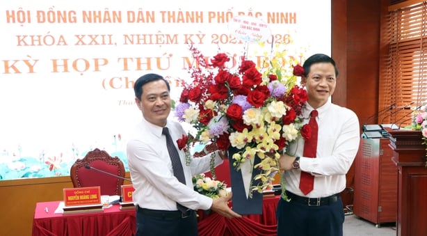Ông Vương Quốc Tuấn, Phó Chủ tịch Thường trực UBND tỉnh Bắc Ninh (bên phải) tặng hoa chúc mừng tân Chủ tịch UBND TP Bắc Ninh Nguyễn Mạnh Hiếu.