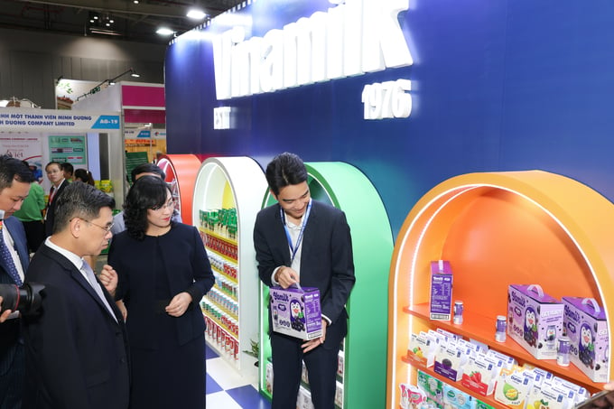 Vo Trung Hieu introducing Vinamilk's export products to Phan Thi Thang, Deputy Minister of Industry and Trade, and other delegates visiting the exhibition.