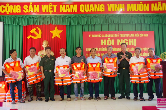 Bộ đội Biên phòng tỉnh Bình Định tặng áo phao và cờ Tổ quốc cho ngư dân. Ảnh: V.Đ.T.