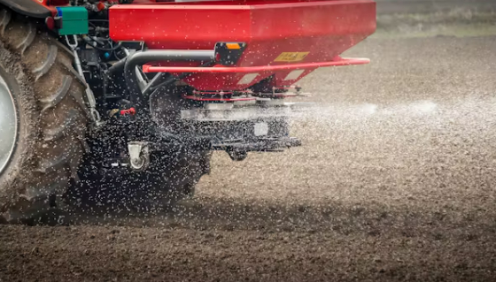 A tractor spreads fertilizer on a field. Precision farming techniques can reduce fertilizer use and the potential for runoff into waterways. Photo: fotokostic/iStock/Getty Images Plus.