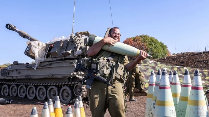 Một người lính Israel di chuyển một quả đạn pháo cỡ nòng 155mm hôm 26/6 gần biên giới Israel - Lebanon, nơi quân đội Israel đang giao tranh với lực lượng Hezbollah. Ảnh: AFP.
