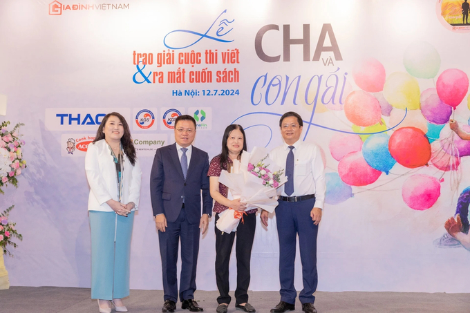 Tổng Biên tập Báo Nhân dân Lê Quốc Minh và Trưởng Ban tổ chức Hồ Minh Chiến trao Giải Nhất cho tác giả Lưu Khánh Thơ với tác phẩm Cha tôi và những kỷ niệm sống mãi cùng thời gian. Ảnh: BTC