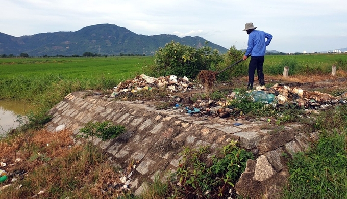 Công nhân thủy nông vớt rác từ kênh mương lên bờ để xử lý, đảm bảo nguồn nước lưu thông. Ảnh: KS.