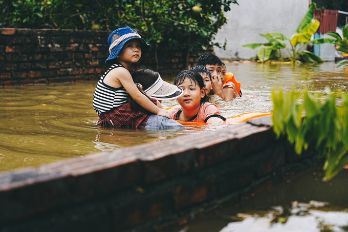 Các gia đình không có thuyền để di chuyển đã lựa chọn cách tự lội dưới dòng nước để sơ tán. Ảnh: Đức Minh. 