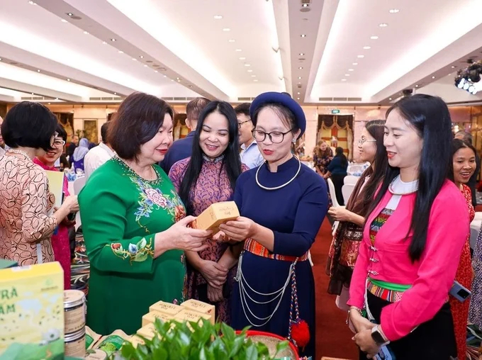 Mrs. Cao Xuan Thu Van, Chairwoman of the Vietnam Cooperative Alliance (wearing a green ao dai), views cooperative products. Photo: Organizing Committee.