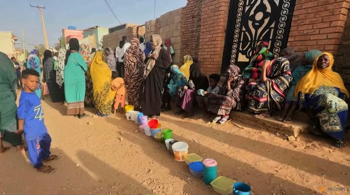 Residents wait to collect food in containers from a soup kitchen in Omdurman, Sudan, on Mar 11, 2024.