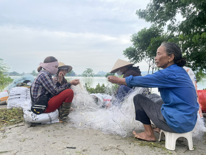 Người dân tranh thủ đan lưới, bắt cá vì không thể ra đồng như ngày thường. Ảnh: Minh Toàn.