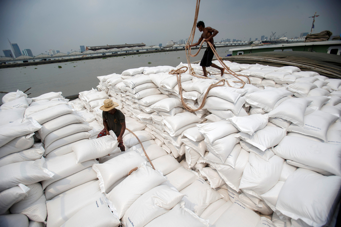 Công nhân bốc dỡ những bao gạo từ xà lan xuống tàu chở hàng trên sông Chao Phraya ở Bangkok. Ảnh: Reuters.