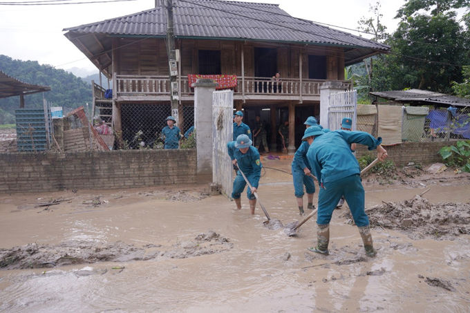 Lực lượng dân quân tự về hỗ trợ người dân dọn dẹp nhà cửa, di chuyển khối lượng bùn đất ra khỏi nhà. Ảnh: Hà Trần.