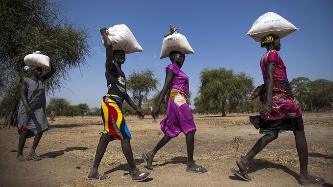 Women carry food in gunny bags after visiting an aid distribution center in South Sudan. 