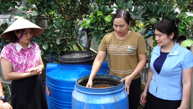 Do Thi Dao ferments organic compost in a 200-liter plastic drum.