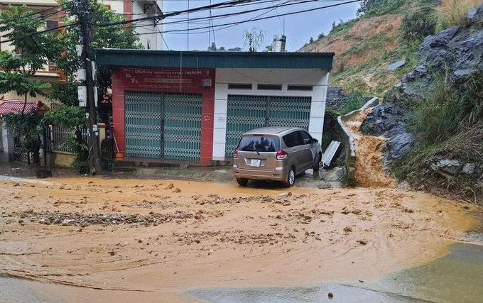 Bùn đất và nước chảy thành dòng từ trên cao đổ xuống nhà dân và ra quốc lộ 4. Ảnh: H.D.