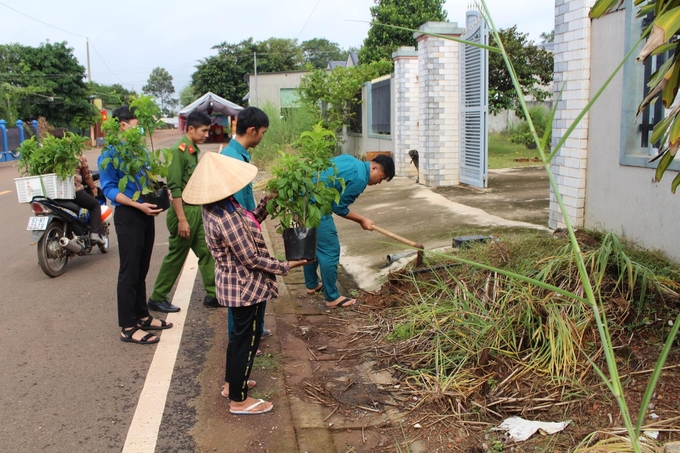 Lực lượng đoàn viên công an và Ban quân sự xã cùng người dân vệ sinh cỏ rác và trồng hoa ven đường. Ảnh: Hồng Thủy.