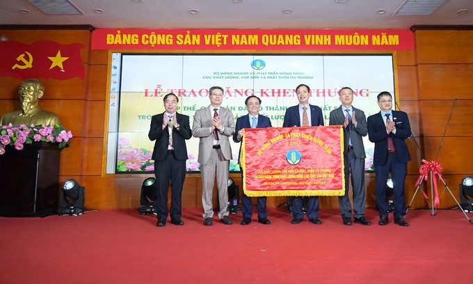 Minister Le Minh Hoan presented a commemorative banner to the NAFIQPM collective. Photo: Tung Dinh.