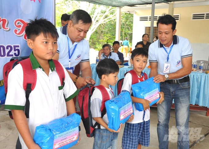 Các thành viên nhóm 'Tiếp sức đến trường' trao quà là dụng cụ học tập, ba lô, sách giáo khoa và đồng phục cho học sinh có hoàn cảnh khó khăn Trường Tiểu học Đông Hòa 1. Ảnh: Trung Chánh.