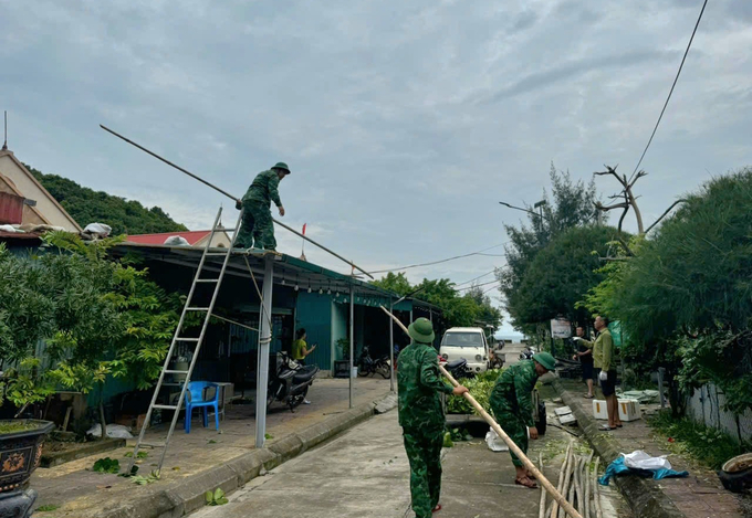 Cán bộ, chiến sỹ Đồn Biên phòng đảo Trần giúp người dân chằng chống nhà cửa, ứng phó bão số 3. Ảnh: Vũ Cường