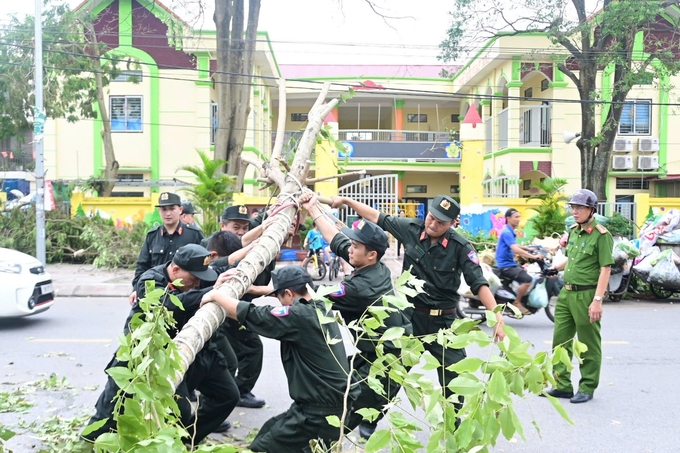 Lực lượng công an hỗ trợ người dân dọn cây ngã đổ trên phố. Ảnh: CTV.