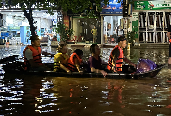 Bà Nguyễn Thị Tuất cùng 2 cháu nhỏ về tới điểm an toàn trong đêm. Ảnh: Quang Linh.