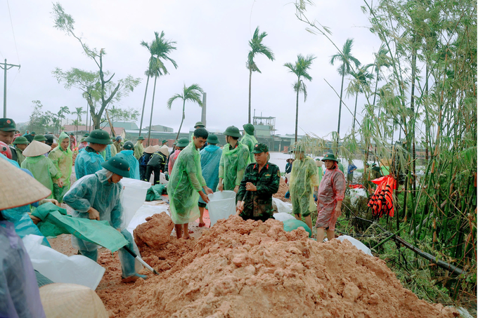 Hàng trăm người dân cùng chính quyền địa phương, bộ đội và công an đắp con lươn ngăn nước lũ dâng cao.