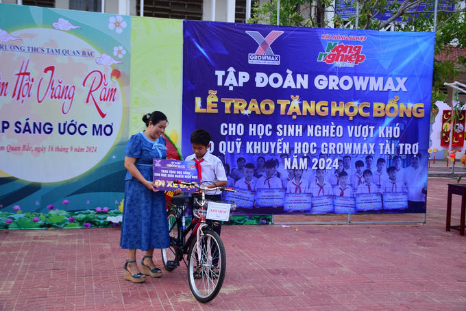 Vợ anh Nguyễn Thanh Minh, đại lý của Tập đoàn GrowMax ở khu phố Công Thạnh, phường Tam Quan Bắc (thị xã Hoài Nhơn, Bình Định), trao học bổng chiếc đạp cho 1 học sinh Trường THCS Tam Quan Bắc. Ảnh: V.Đ.T.