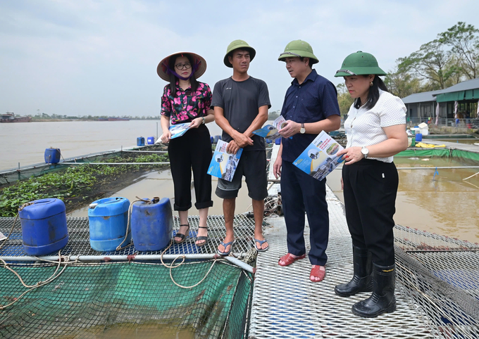 Cơ quan chức năng thực hiện phát tờ rơi đến tận tay các hộ nuôi cá lồng bè. Ảnh: Tùng Đinh.