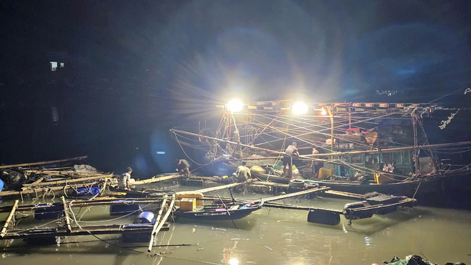 Exploiting the light from a squid fishing boat, fishermen prepare their gear for fishing. Photo: Van Viet.