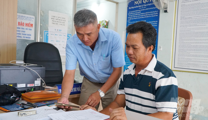 Staffs at the Tan Phuoc Fishing Port in Long Dien District providing local fishermen with instructions to declare electronic logs and trace the origin of their catch via mobile phone. Photo: Le Binh.