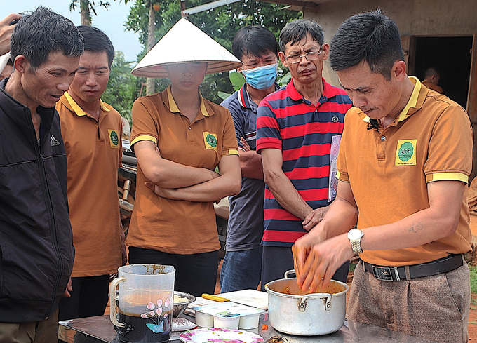 Mr. Ha Cong Xa (orange shirt, right) instructs members on how to mix biological chemicals for coffee. Photo: Hong Thuy.