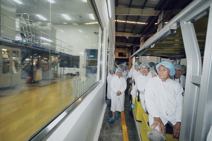 The group observing the various stages of processing, filling, and packaging at the factory from behind glass windows. These areas are fully sealed to minimize human interaction and ensure product quality and food safety. All operations at the factory are carried out by robots and automated machinery. Photo: Vi Nam.