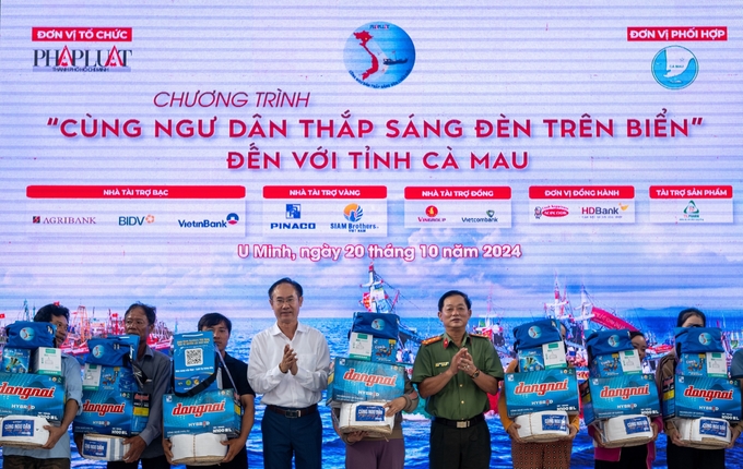 Ông Bùi Thanh Quang, Trưởng Văn phòng đại diện Agribank khu vực Tây Nam bộ (bên trái), tặng quà cho các ngư dân tại xã Khánh Hội, huyện U Minh, tỉnh Cà Mau. Ảnh: Kim Anh.