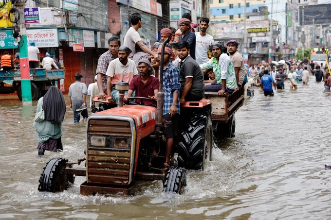 Người dân sử dụng máy kéo để di chuyển qua một con phố bị ngập lụt ở Feni, Bangladesh hồi tháng 8/2024. Ảnh: Reuters.