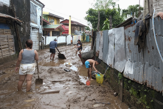 Người dân Albay dọn dẹp bùn đất trong làng sau khi bão Trà Mi quét qua. Ảnh: AP News.