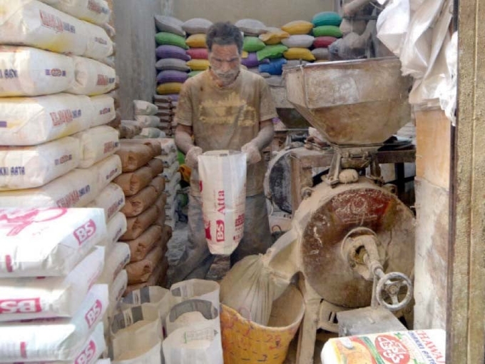 A worker grinds wheat at a shop in the Saddar area of Karachi to make whole-grain flour. Photo: Jalal Qureshi.