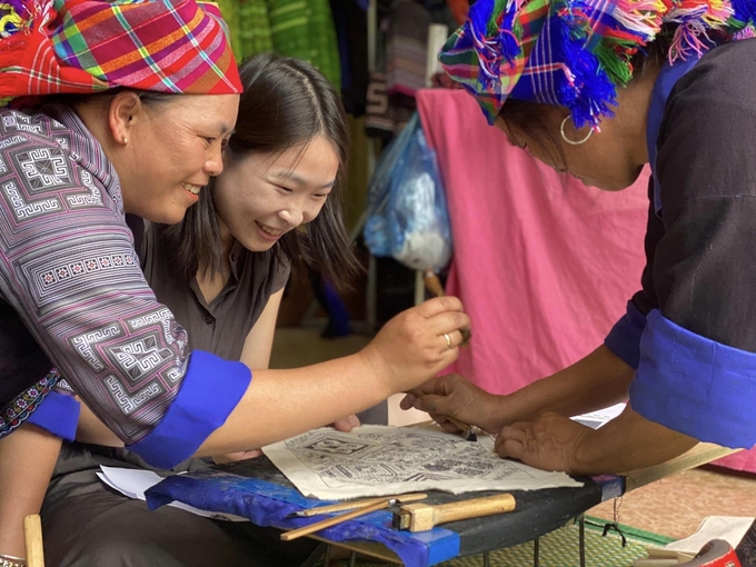 Ms. Hong Hong, a Chinese tourist, is interested in the painting of Hmong women. Photo: Thanh Tien.